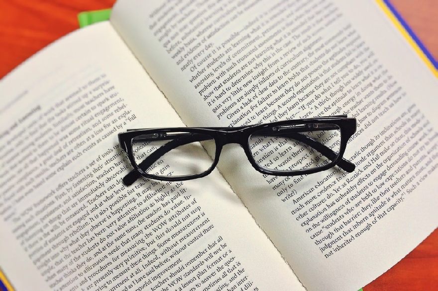 Schwarze Brille auf einem aufgeschlagenen Buch