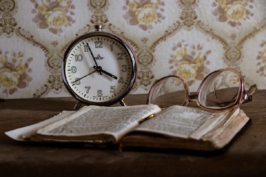 Retro glasses with alarm clock and book