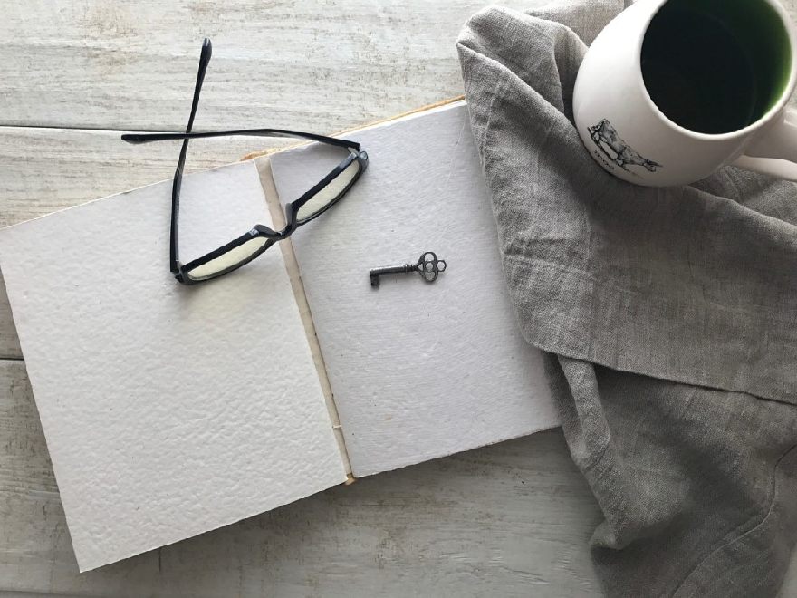 Brille auf einem Buch und ein Kaffee