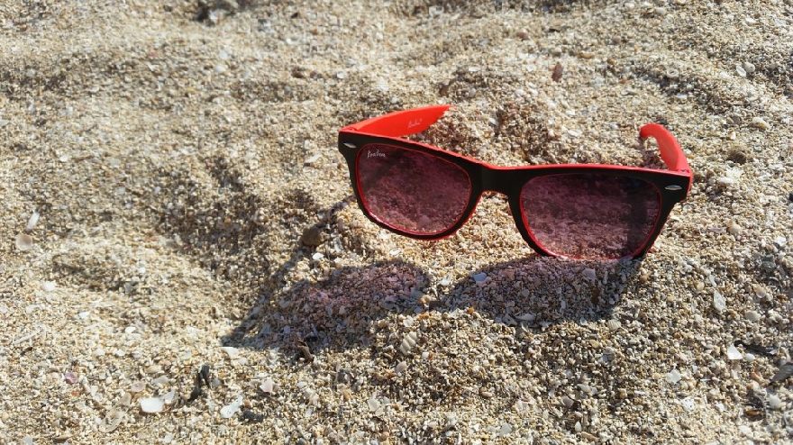 Lunettes de soleil rouges dans le sable