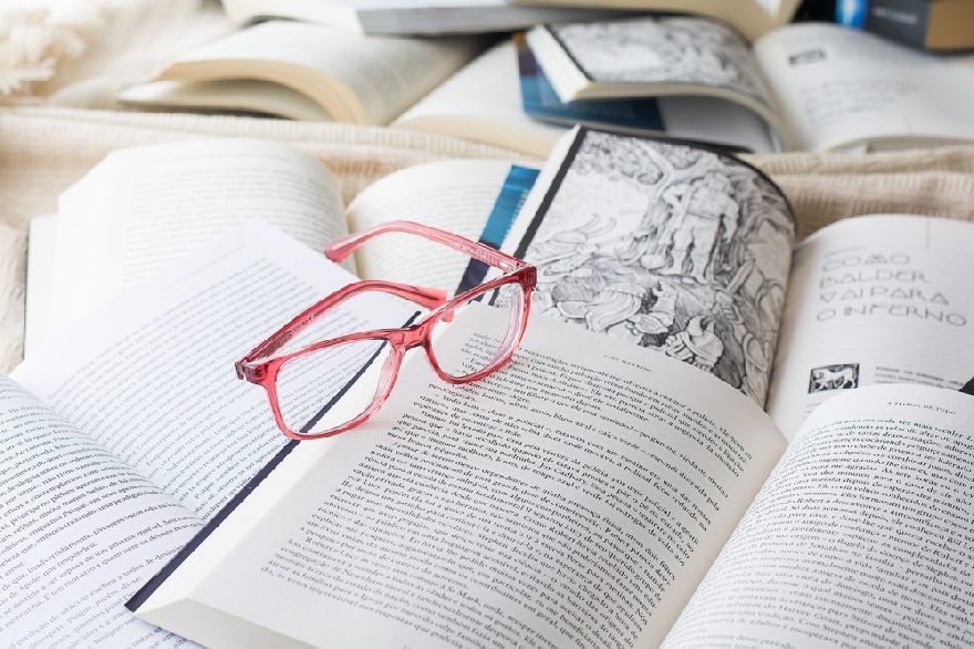 Eine rosa Brille auf vielen aufgeschlagenen Büchern