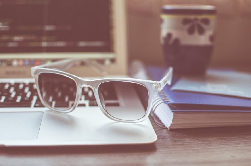 Sunglasses and a laptop computer behind them